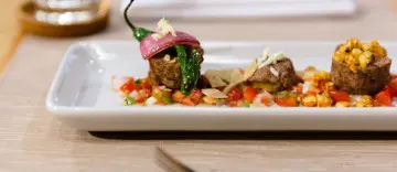 Gourmet stuffed pepper appetizer with colorful garnish on a white plate.