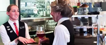 A woman enjoying a glass of wine at a bar counter.