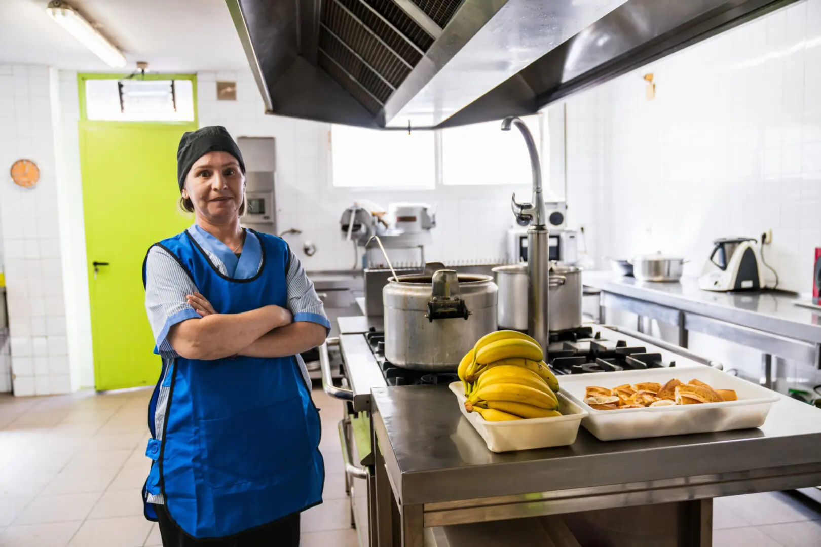 Cook standing in commercial kitchen with bananas.