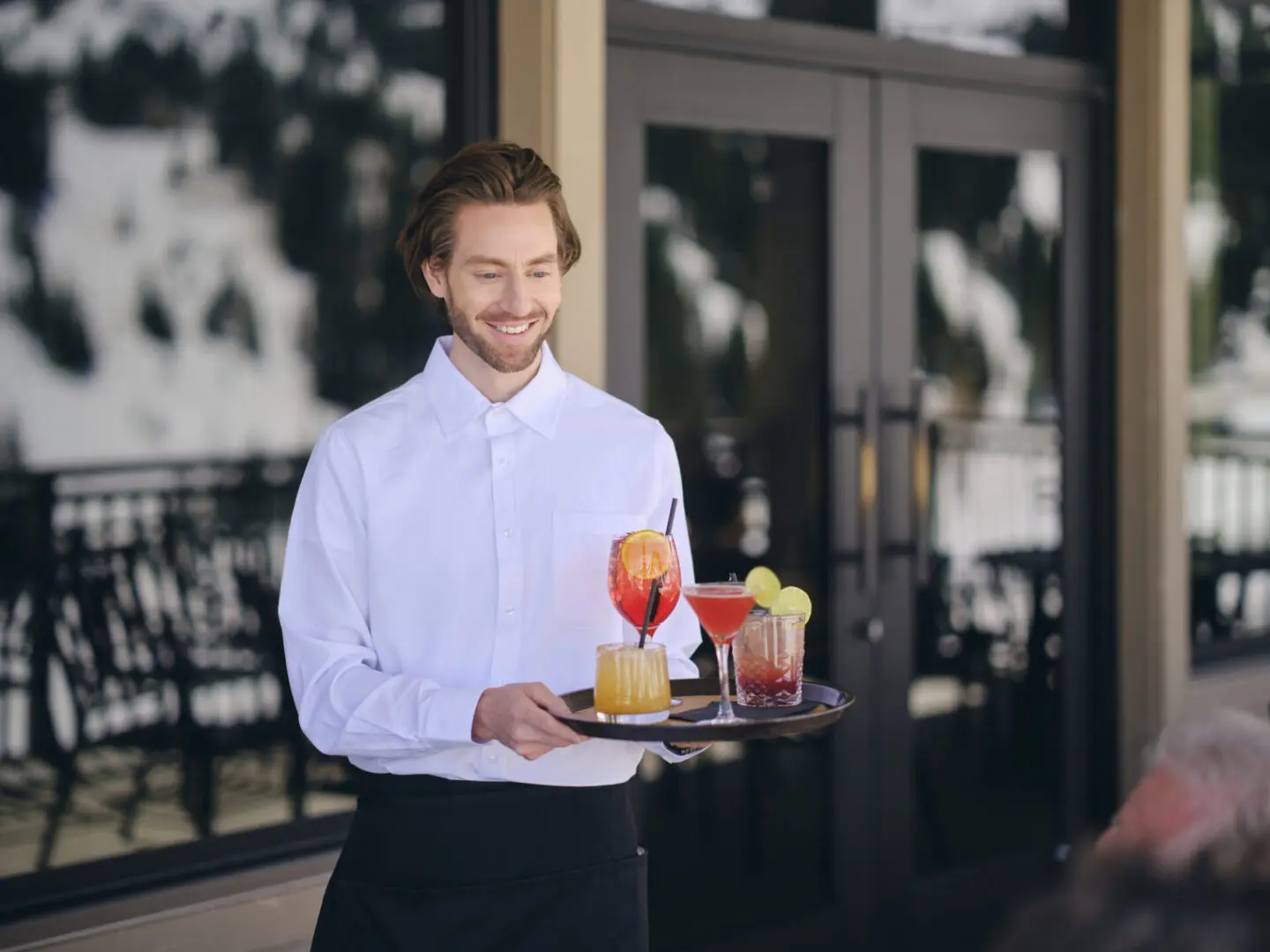 Waiter carrying tray with colorful drinks.