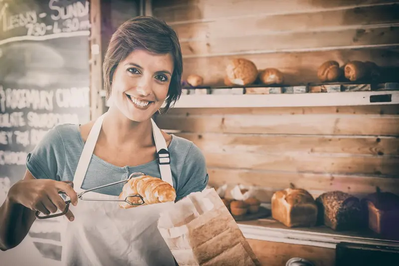 Baker placing bread in paper bag.