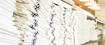 Stacked white towels on display shelf.