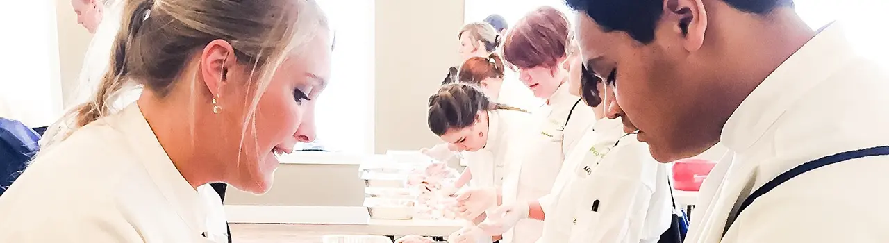Students practicing in a culinary classroom setting.