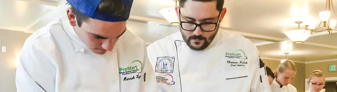 Chefs preparing food in a kitchen setting.